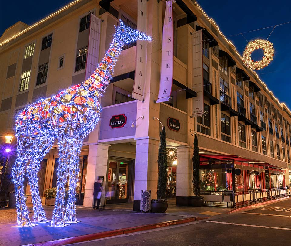 Lit giraffe light sculpture on a street at Santana Row