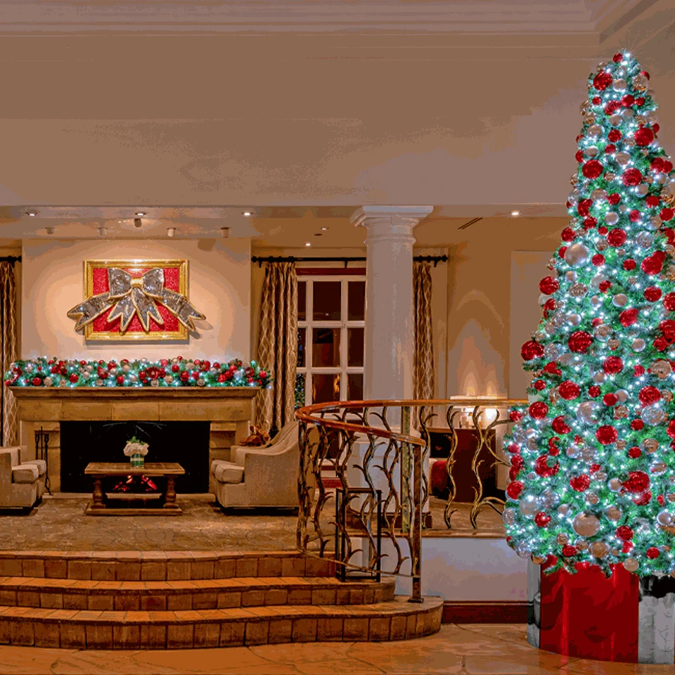 Lobby with a fireplace, garland and a red and white Christmas tree at the Fairmont Scottsdale Princess